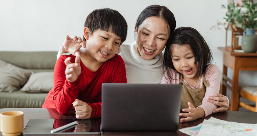 Mother with two children sitting in front of a laptop 