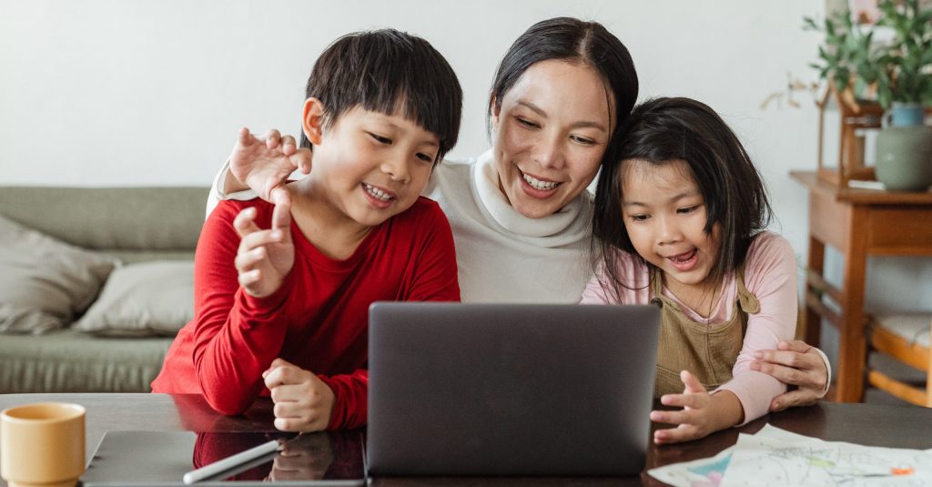 Madre con due bambini seduta davanti a un laptop